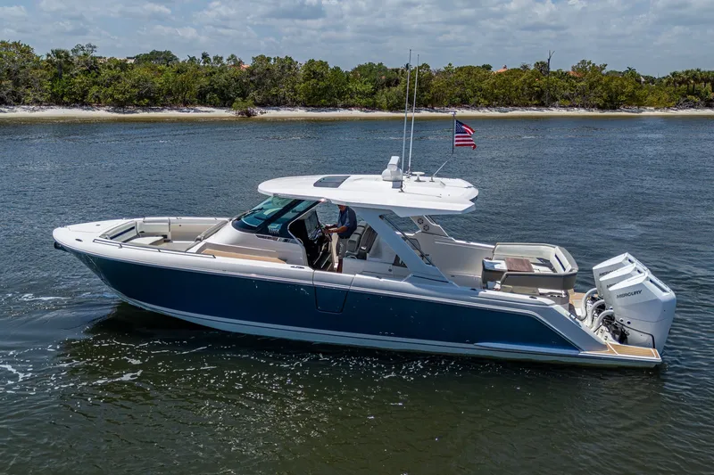 The Image of 2024 Tiara Yachts 38 LS cruising on a serene waterway with lush greenery. - 0