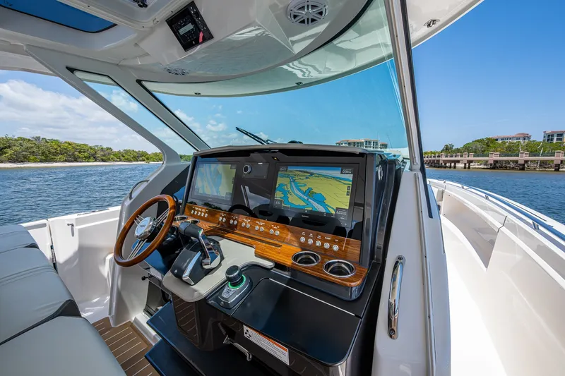 Slide: The Image of 2024 Tiara Yachts 38 LS helm with navigation display, wooden accents, and scenic water view. - 15