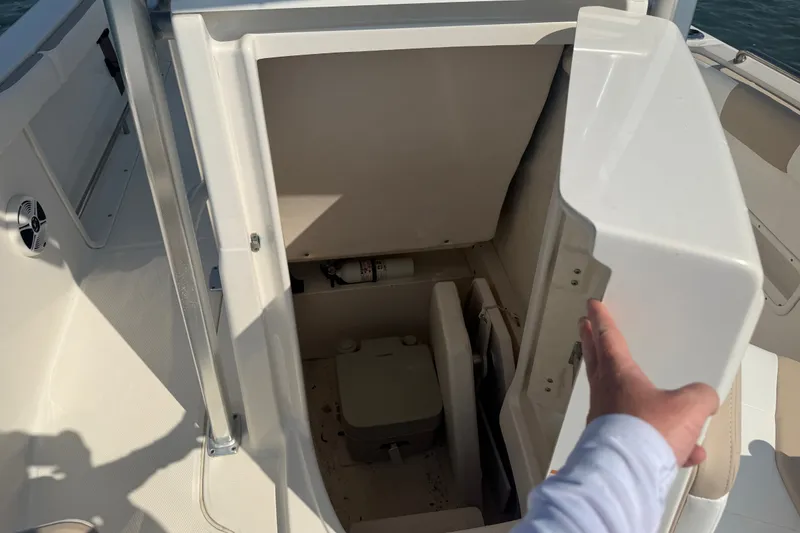 Slide: The Image of 2018 Robalo R222 Center Console boat storage compartment with open door, revealing interior space. - 32
