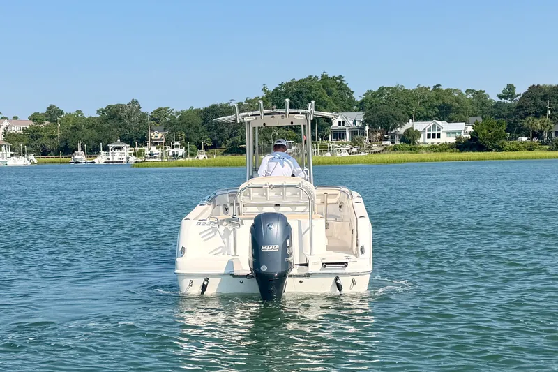 Slide: The Image of 2018 Robalo R222 Center Console boat cruising on a serene lake with houses in the background. - 13