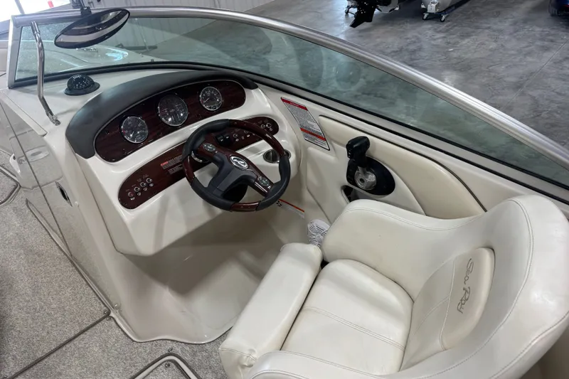 Slide: The Image of 2008 Sea Ray 240 Sundeck cockpit with steering wheel and gauges, featuring white seating. - 8