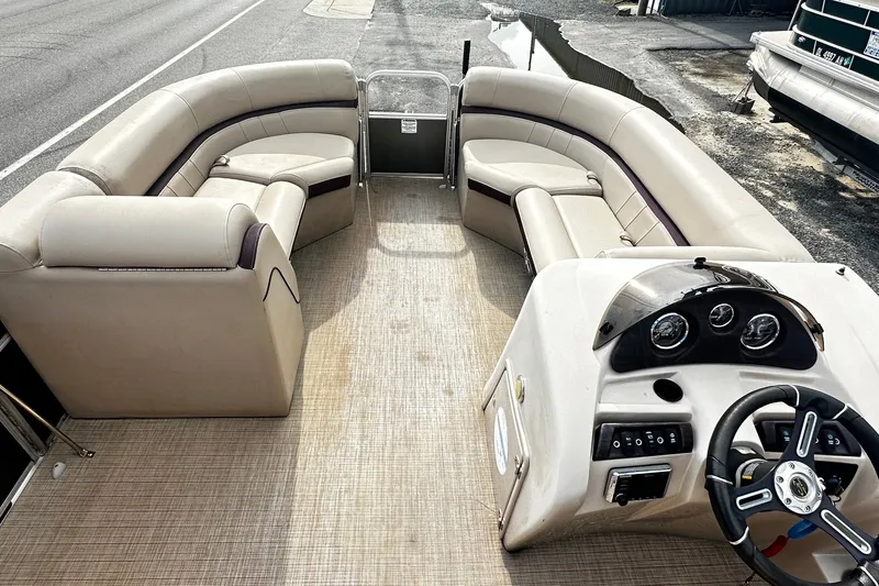 Slide: The Image of 2018 Berkshire Pontoon boat interior with beige seating and steering console. - 7