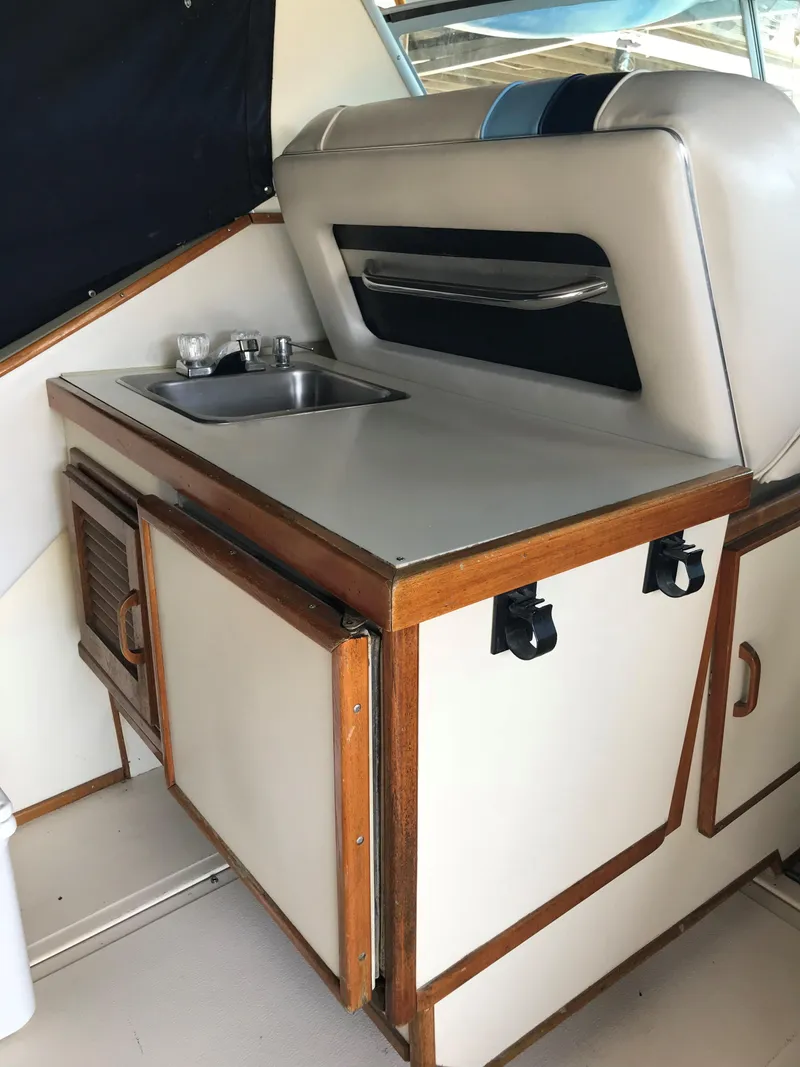 Slide: The Image of The 1987 Sea Ray 390 Express Cruiser features a compact kitchenette with a sink and storage. - 11