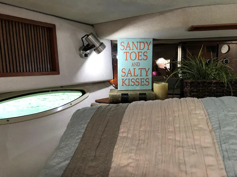Slide: The Image of Interior of a 1987 Sea Ray 390 Express Cruiser with a cozy bed and decorative sign. - 17