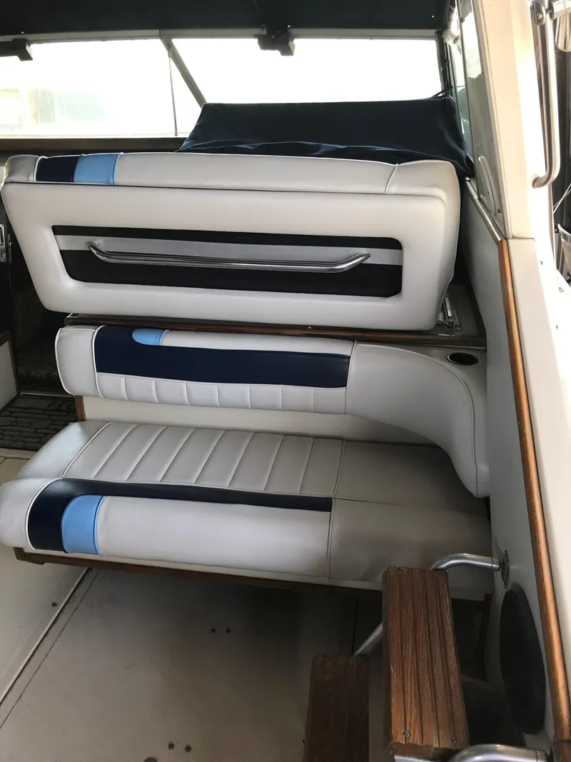 Slide: The Image of The interior of the 1987 Sea Ray 390 Express Cruiser features tiered, cushioned seating in white and blue. - 12