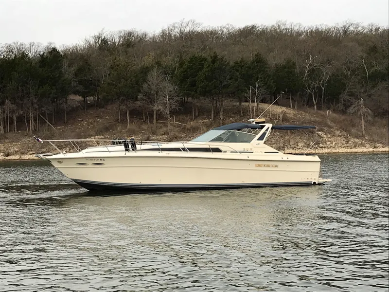 Slide: The Image of A 1987 Sea Ray 390 Express Cruiser on calm water, with a wooded shoreline in the background. - 3