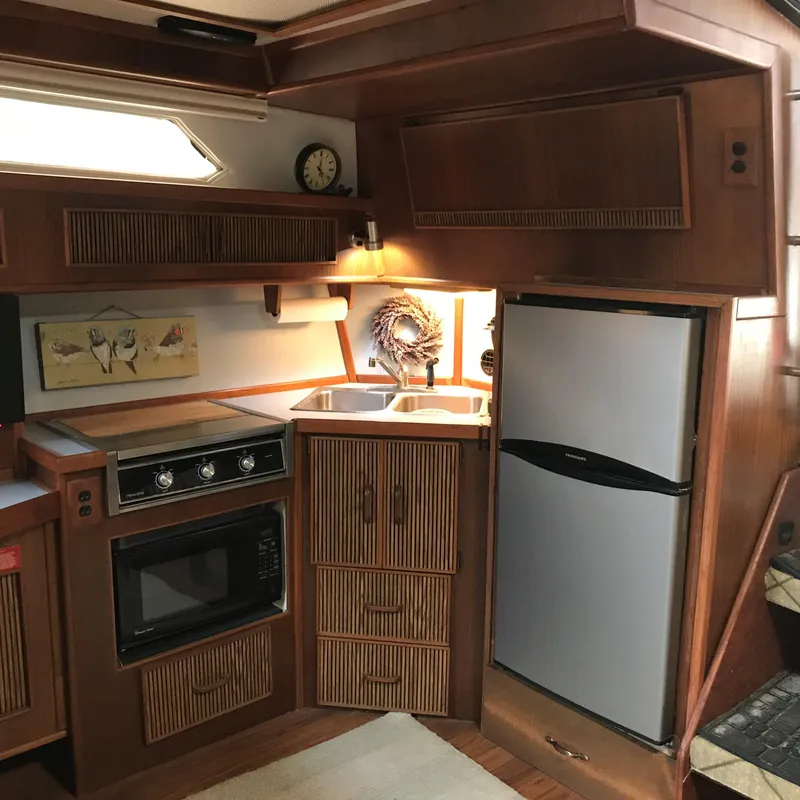 Slide: The Image of The galley of a 1987 Sea Ray 390 Express Cruiser with wood cabinets, stove, and refrigerator. - 15