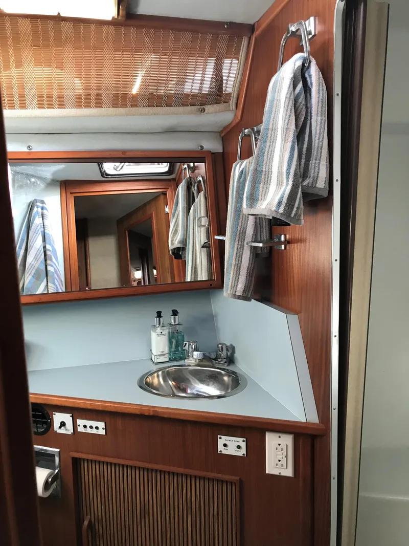 Slide: The Image of The image shows the bathroom of a 1987 Sea Ray 390 Express Cruiser with a sink and towels. - 31