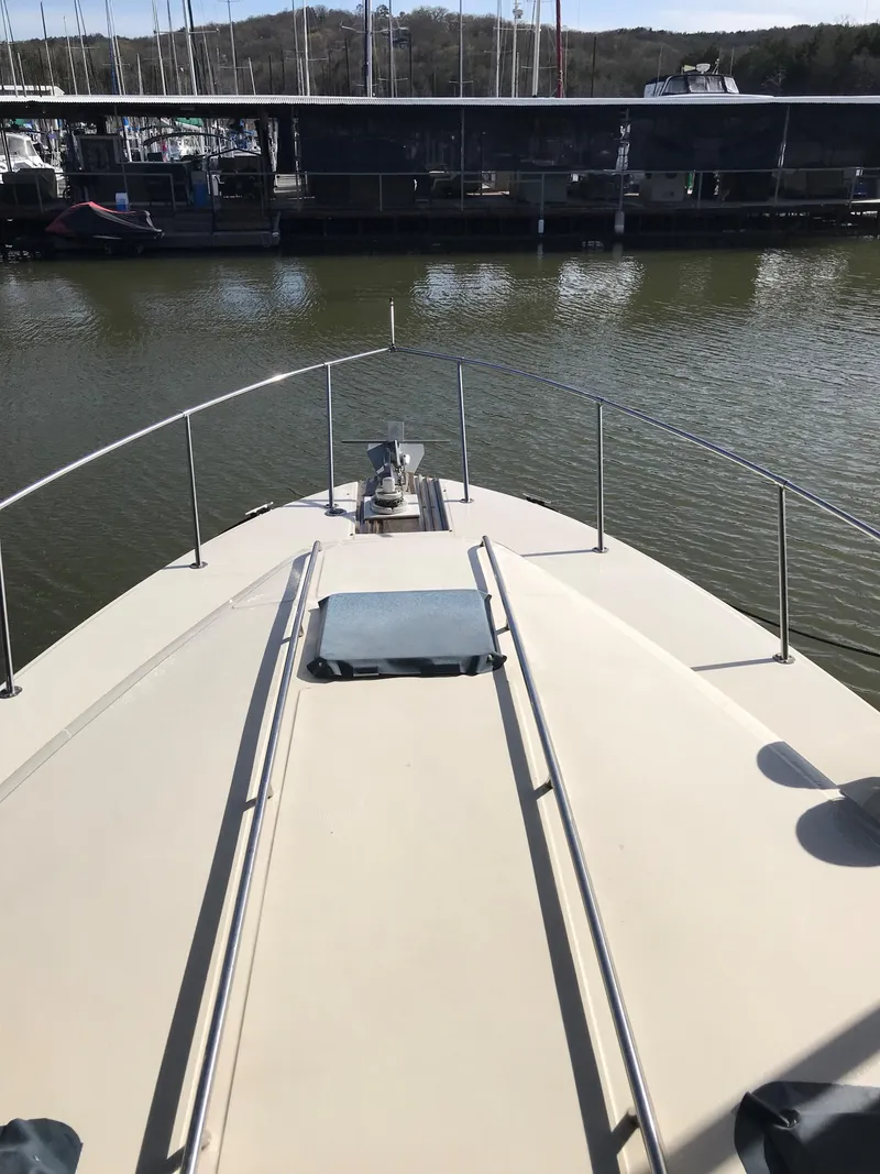 Slide: The Image of Bow view of a 1987 Sea Ray 390 Express Cruiser, docked, featuring railings and anchor. - 6