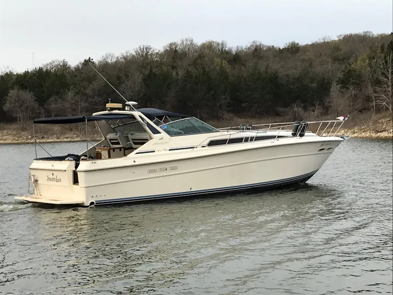 The Image of A 1987 Sea Ray 390 Express Cruiser on calm water, surrounded by trees. - 0