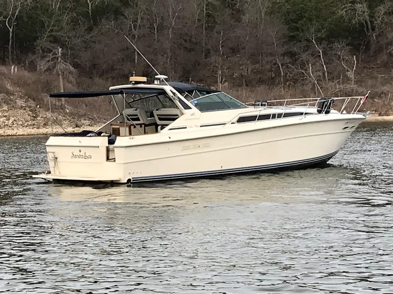 Slide: The Image of A 1987 Sea Ray 390 Express Cruiser on calm water, surrounded by trees. - 4