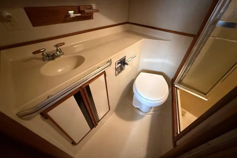 Slide: The Image of 1986 Sea Ray 410 Aft Cabin bathroom with sink, toilet, and shower. - 48
