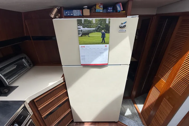 Slide: The Image of 1986 Sea Ray 410 Aft Cabin kitchen with refrigerator and calendar, showcasing cozy interior. - 35