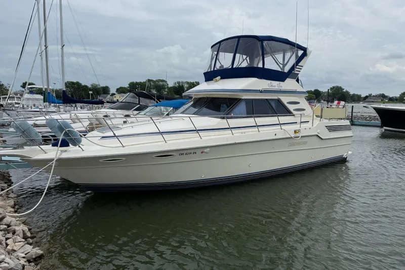The Image of 1986 Sea Ray 410 Aft Cabin yacht docked in a marina, featuring a blue canopy. - 0