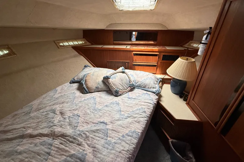 Slide: The Image of 1986 Sea Ray 410 Aft Cabin bedroom with cozy bedding and wooden cabinetry. - 36