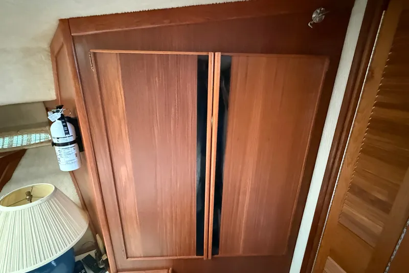 Slide: The Image of Wooden cabinet interior of 1986 Sea Ray 410 Aft Cabin with fire extinguisher and lamp. - 38