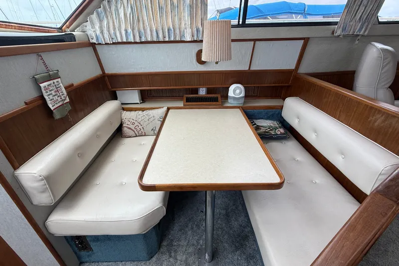 Slide: The Image of 1986 Sea Ray 410 Aft Cabin interior with dining area and cushioned seating. - 25