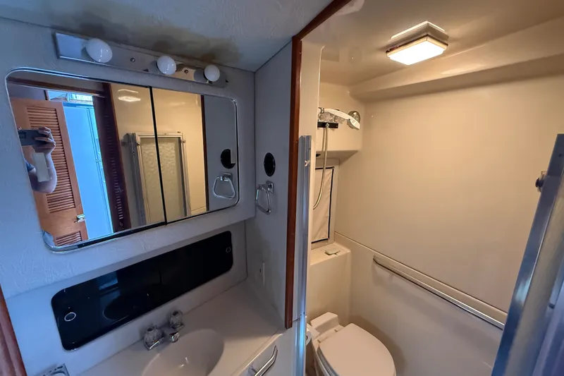 Slide: The Image of 1986 Sea Ray 410 Aft Cabin bathroom with mirror, sink, and shower area. - 39