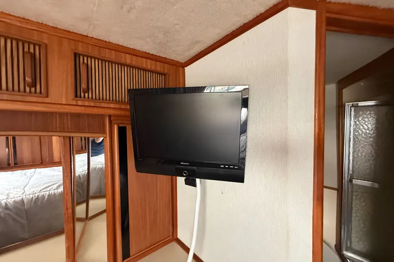 Slide: The Image of 1986 Sea Ray 410 Aft Cabin interior with mounted TV and wooden cabinetry. - 46