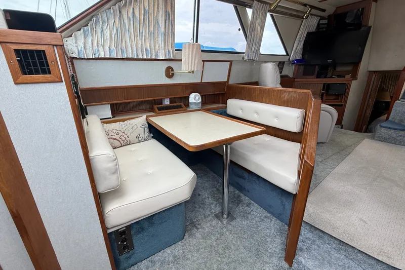 Slide: The Image of 1986 Sea Ray 410 Aft Cabin interior with cozy dining area and plush seating. - 26