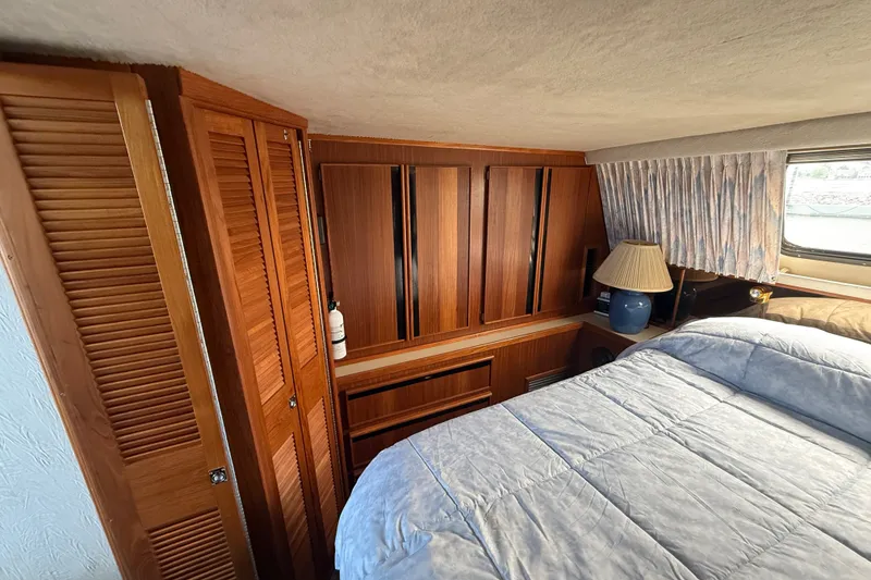 Slide: The Image of 1986 Sea Ray 410 Aft Cabin interior with wood cabinetry and cozy bedding. - 44