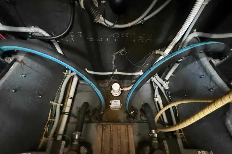 Slide: The Image of Engine room of a 1986 Sea Ray 410 Aft Cabin boat with visible hoses and wiring. - 58