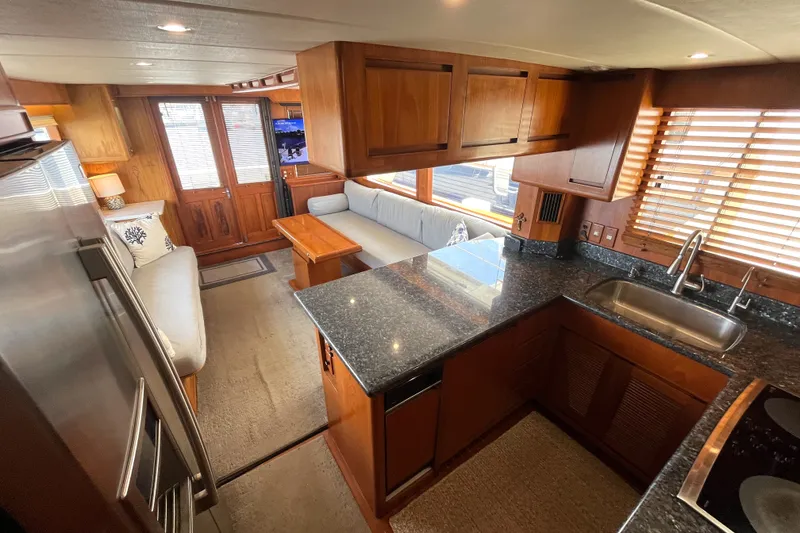 Slide: The Image of The interior of a 2002 Grand Alaskan 53 RPH features an elegant kitchen with granite countertops and wooden cabinetry. - 8