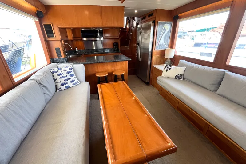 Slide: The Image of The 2002 Grand Alaskan 53 RPH salon features two sofas, a wooden table, and a kitchen area. - 5