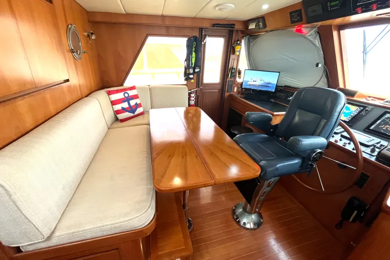 Slide: The Image of The interior of a 2002 Grand Alaskan 53 RPH features a cozy seating area and helm station. - 14