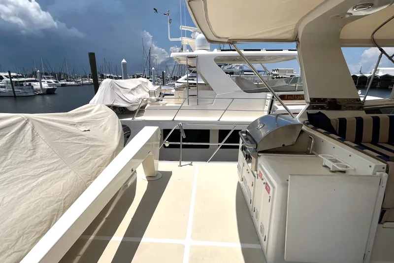 Slide: The Image of The image shows the deck of a 2002 Grand Alaskan 53 RPH in a marina, featuring a grill and covers. - 47