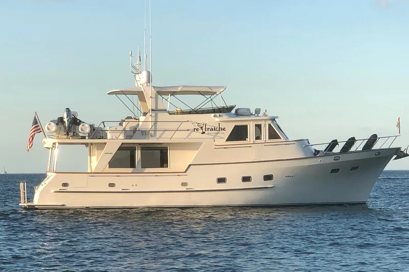 The Image of A 2002 Grand Alaskan 53 RPH yacht on calm water, featuring flags and a sun deck. - 0