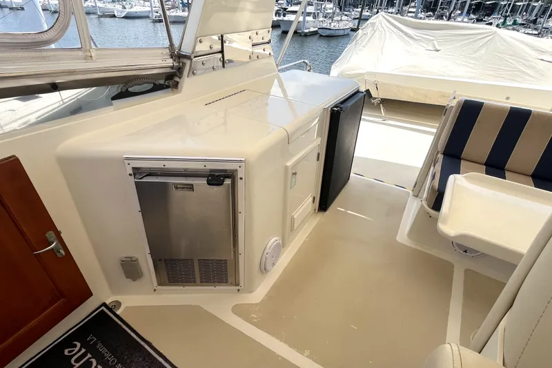 Slide: The Image of The image shows the deck of a 2002 Grand Alaskan 53 RPH with seating area and refrigerator. - 48