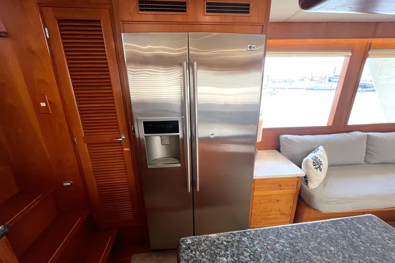Slide: The Image of The interior of a 2002 Grand Alaskan 53 RPH features a stainless steel refrigerator and a sofa. - 12