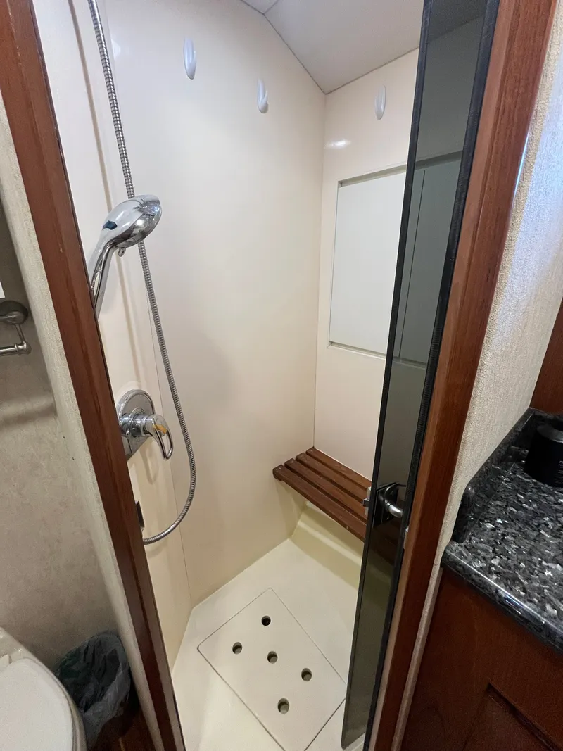 Slide: The Image of The shower in the 2002 Grand Alaskan 53 RPH features a wooden bench and handheld showerhead. - 33