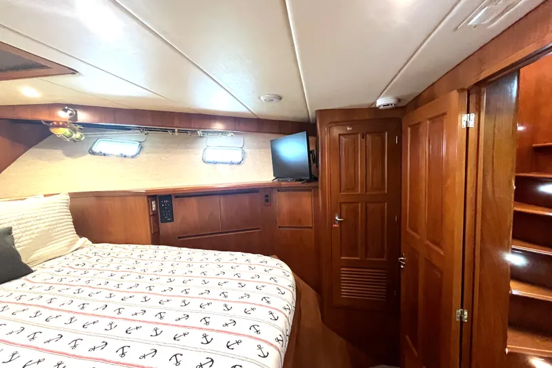 Slide: The Image of The cabin of a 2002 Grand Alaskan 53 RPH with wood paneling and a bed with anchor-patterned bedding. - 26