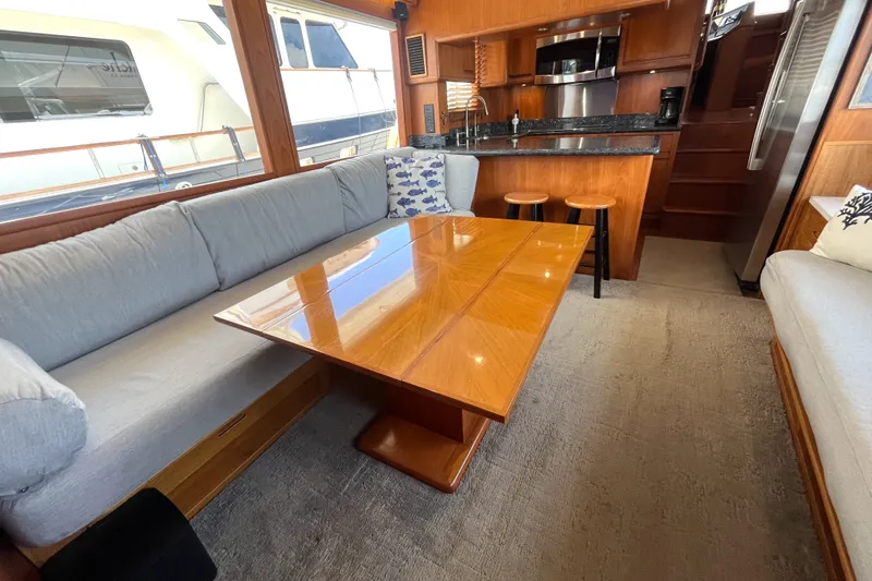 Slide: The Image of The salon of a 2002 Grand Alaskan 53 RPH with a wooden table, gray sofas, and a galley. - 6