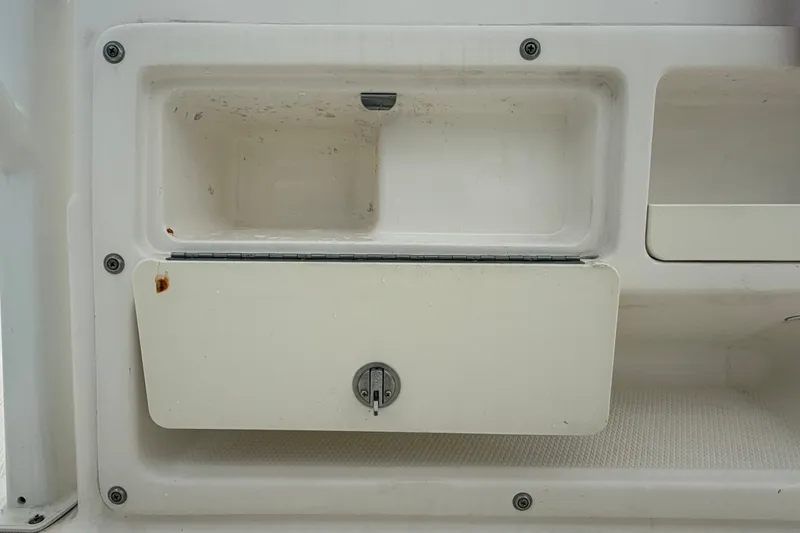 Slide: The Image of 2019 Robalo R222 Center Console storage compartment with latch and slight rust. - 30
