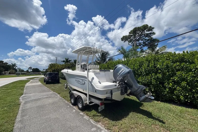 Slide: The Image of 2019 Robalo R222 Center Console boat on trailer, parked roadside under blue sky. - 4