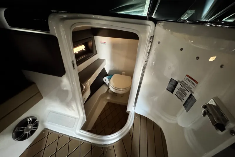 Slide: The Image of Interior of 2022 Sea Ray SLX 280 boat featuring a compact bathroom with toilet. - 18