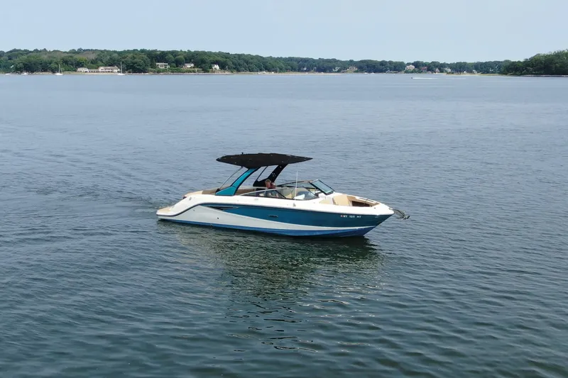 Slide: The Image of 2022 Sea Ray SLX 280 boat cruising on a calm lake with scenic shoreline. - 2