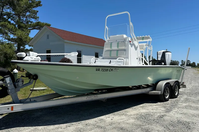 Slide: The Image of 2016 Shallow Sport 24 Modified V boat on trailer, parked outdoors under clear sky. - 15