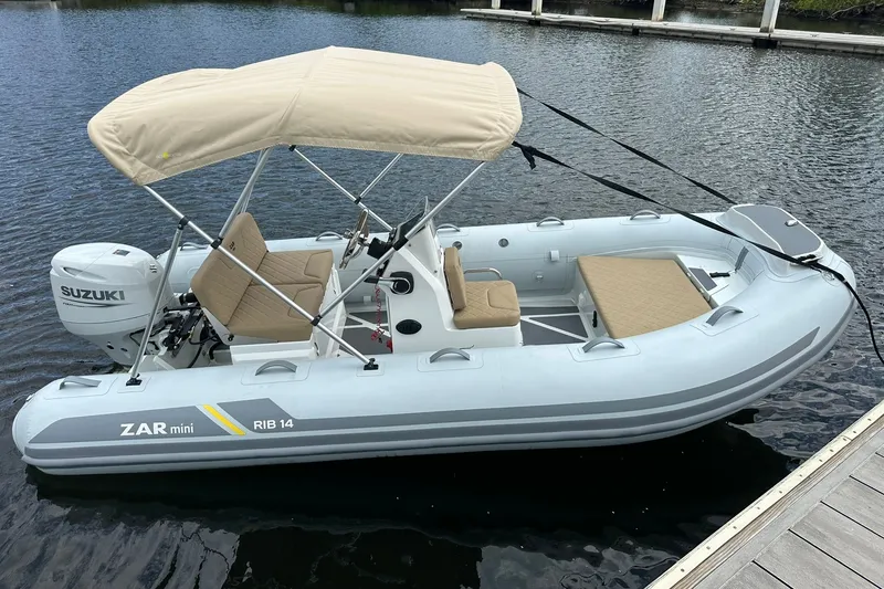 The Image of 2027 ZAR Mini RIB 14 inflatable boat with Suzuki motor, docked on calm water. - 5