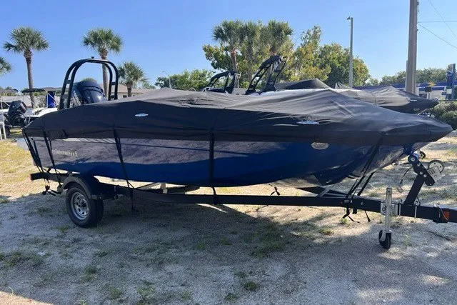 The Image of 2027 Bayliner Element E18 boat covered on trailer, parked outdoors with palm trees in background. - 0