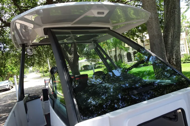 Slide: The Image of 2025 Monterey Elite 27 OB boat with sleek design and modern features, parked under trees. - 29
