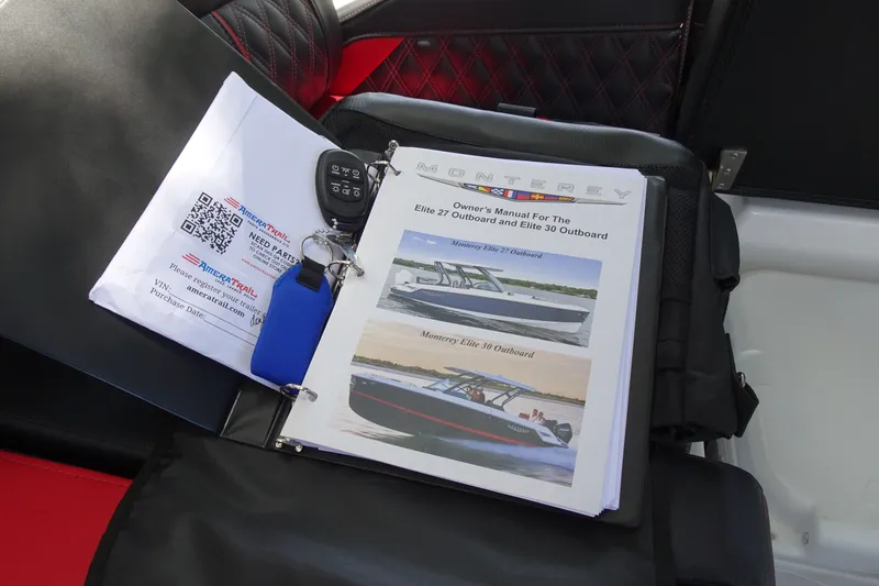 Slide: The Image of Owner's manual for 2025 Monterey Elite 27 OB on boat seat with key fob. - 31