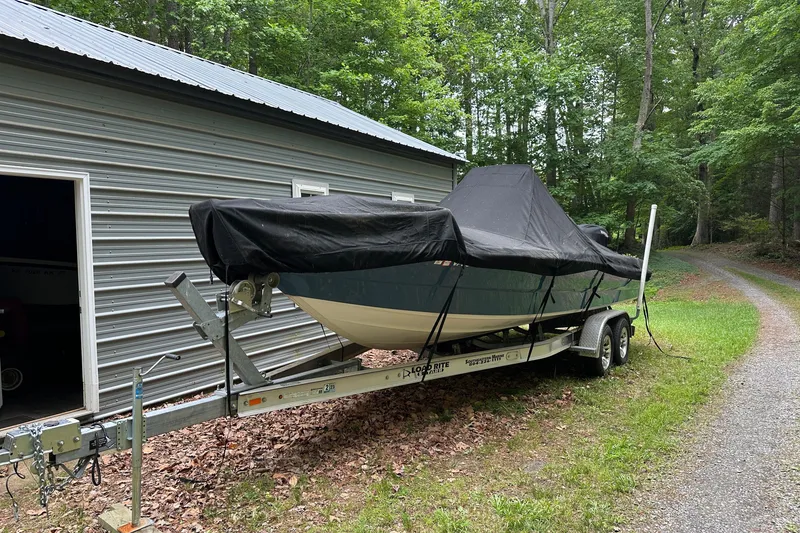 Slide: The Image of Covered 2008 Triton 240 LTS Pro boat on trailer beside metal building, surrounded by trees. - 13