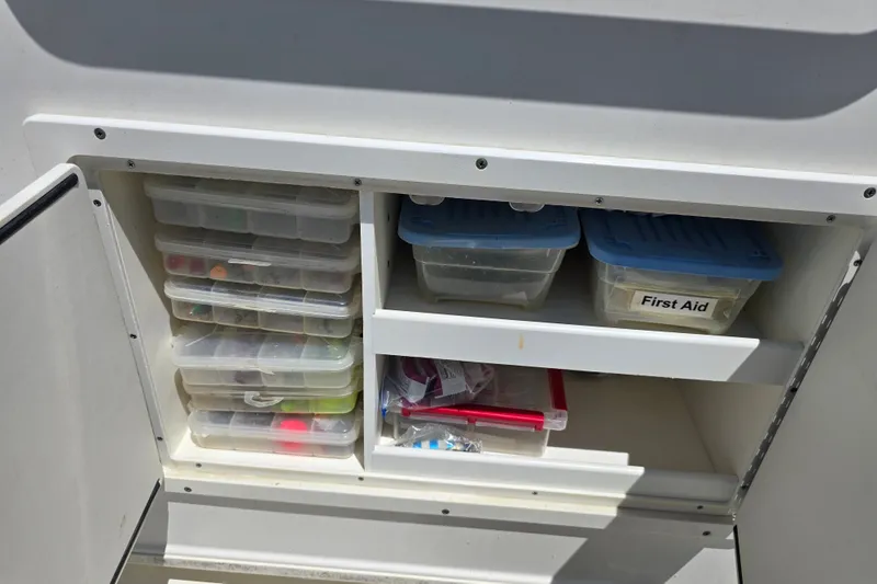 Slide: The Image of Storage compartment in a 2008 Triton 240 LTS Pro boat with organized tackle boxes and first aid kit. - 28