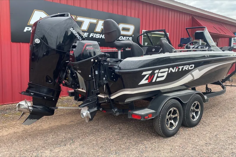 Slide: The Image of 2019 Nitro ZV19 Pro fishing boat with Mercury engine, parked outside a red building. - 2