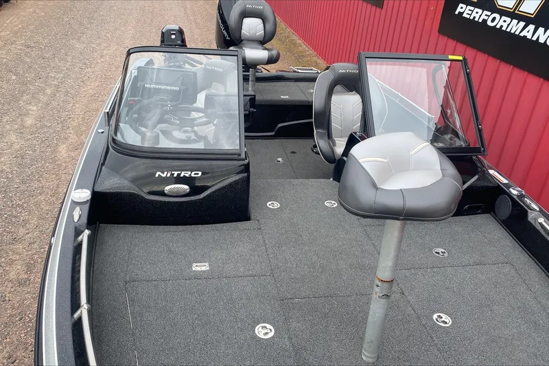 Slide: The Image of 2019 Nitro ZV19 Pro fishing boat with seating and control panel, parked near a red wall. - 6