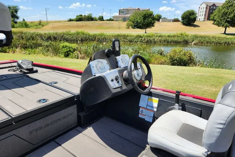 Slide: The Image of 2027 Tracker Pro 170 boat interior with steering wheel, dashboard, and seating by a scenic lake. - 35